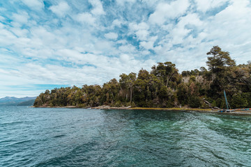 Obraz premium Stunning landscape of a blue water glacier lake, with a view of the snowy mountains, and surrounded by lush Andean forest, in the wild Patagonia of Argentina, South America.