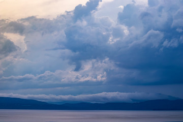 Fototapeta premium Dramatic clouds over lake and mountains at dusk