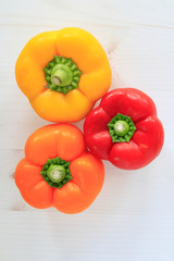 Red, yellow and orange bell peppers on neutral background with copy space