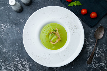 Cream of broccoli soup on dark grey concrete table