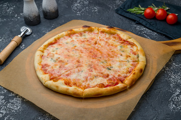 Pizza Quattro formaggi on the board on dark grey concrete table