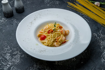 spaghetti with shrimp on dark grey concrete table