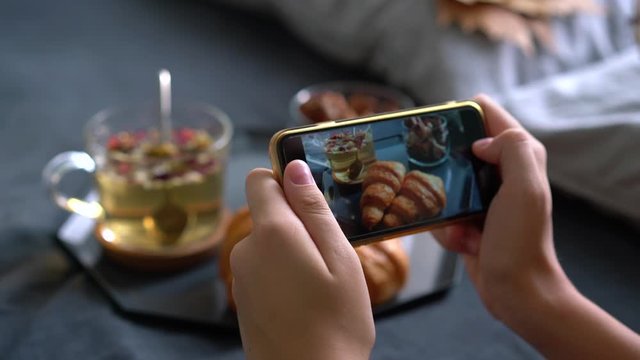 Female hands photographing appetizing food by smartphone. take a photo of cake treat with mobile phone camera for social network.Tilt up shot of woman taking pictures of her breakfast
