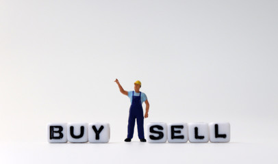 The white cube of 'BUY' and 'SELL' text with miniature people.