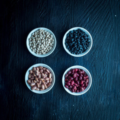 Beans of Different Colors, in Bowls Each Group, on a Black Background