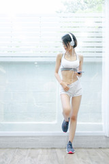 sport woman standing relaxing listening to music and showing muscle body building after exercises in home, fitness concept, sport concept