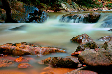 Obraz premium Beautiful River water flowing through stones and rocks at dawn