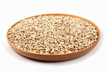 Organic millet grains on brown wood dish on white background.