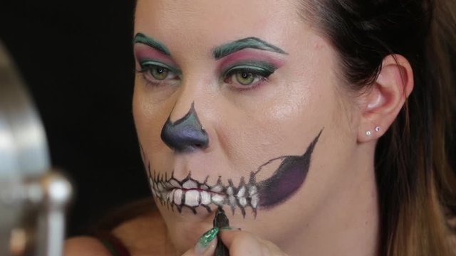 Woman applying halloween makeup to face