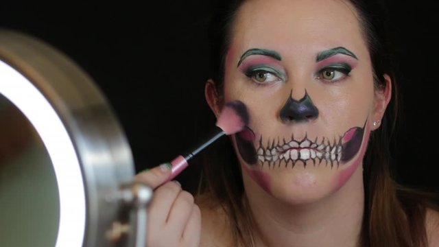 Woman applying halloween makeup to face