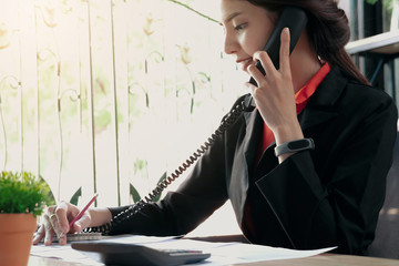 Close up of businesswoman or accountant two hand holding pencil and telephone working on calculator...