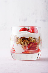 vertical image of breakfast with strawberry, granola and curd on pink background