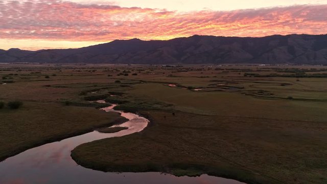 River winding through grassy pasture during colorful sunrise in Wyoming.