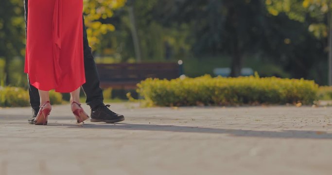 Synchronized steps in the dance. Woman in high heels is dancing in a pair with a man on the street. View from below. Close-up.