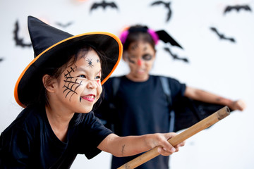 Two cute asian child girls wearing halloween costumes and makeup having fun on Halloween celebration together