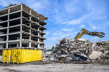 Building House Demolition site Excavator with hydraulic crasher machine and yellow container