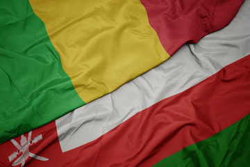 waving colorful flag of oman and national flag of mali.