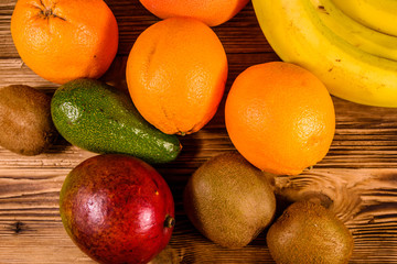 Still life with exotic fruits. Bananas, mango, oranges, avocado, grapefruit and kiwi fruits on wooden table. Top view