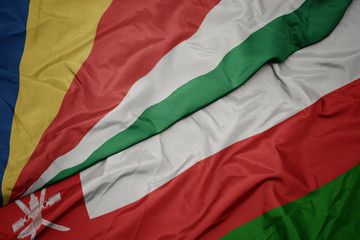 waving colorful flag of oman and national flag of seychelles.