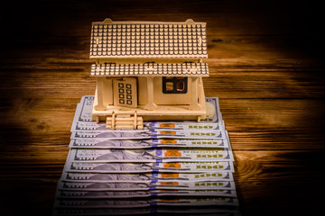 Plywood model of the house and one hundred dollar banknotes. Loan, real estate concept