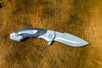 Folding knife on the rustic wooden background