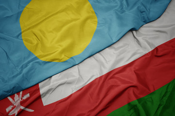 waving colorful flag of oman and national flag of Palau .