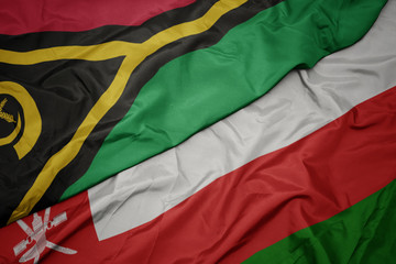 waving colorful flag of oman and national flag of Vanuatu .