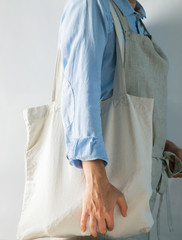 A woman in bright clothes holds a cotton bag made of natural fabric. Rustic natural style. Kinfolk style. Copy space
