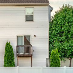 Square frame Facade of home with white wall bay window small balcony and wooden fence