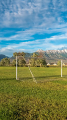 Fototapeta na wymiar Vertical White soccer goal on a grassy sports field with view of snow topped mountain