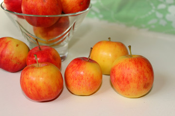 Small red-yellow apples in a vase, white background
