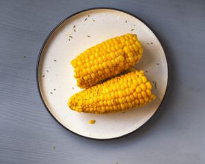 Boiled corn on a ceramic plate, two halves, shot at close range,