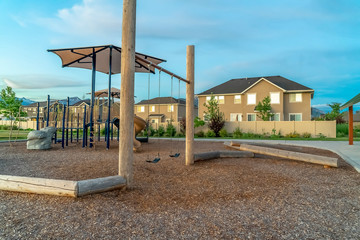 Neighborhood playground with slides and swings against homes and cloudy sky
