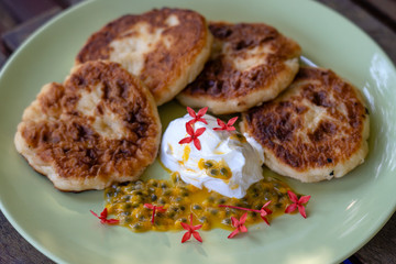 Cheesecakes with passion fruit and sour cream in a green plate for breakfast. Delicious dessert, closeup