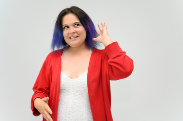 Photo A waist-high portrait of a funny cheerful girl of a young woman with multi-colored hair in a white-red suit on a white background. In the studio, smiling, talking.