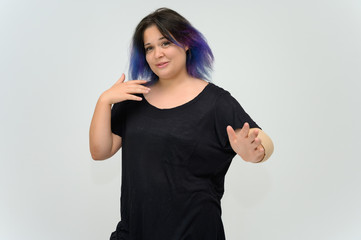 Photo A waist-high portrait of a funny cheerful girl of a young woman with multi-colored hair in a black T-shirt on a white background. In the studio, smiling, talking.