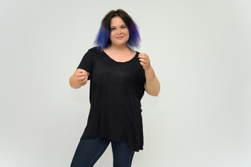 Stock Foto Portrait of a knee-deep funny cheerful girl of a young woman with multi-colored hair in a black T-shirt on a white background. In the studio, smiling, talking.