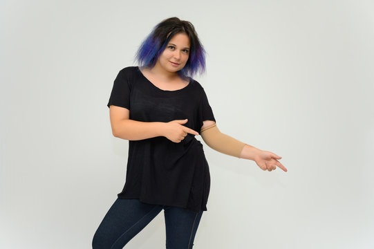 Stock Foto Portrait of a knee-deep funny cheerful girl of a young woman with multi-colored hair in a black T-shirt on a white background. In the studio, smiling, talking.