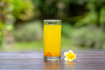 Energy tonic drink with turmeric, ginger, lemon and honey in glass, nature background, close up