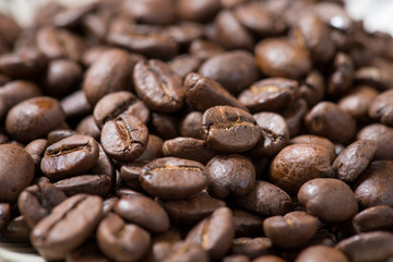 Coffee beans on a plate placed on a wooden table.