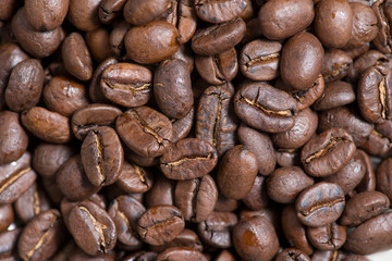 Coffee beans on a plate placed on a wooden table.
