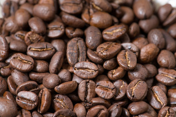 Coffee beans on a plate placed on a wooden table.