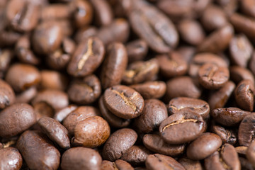 Coffee beans on a plate placed on a wooden table.