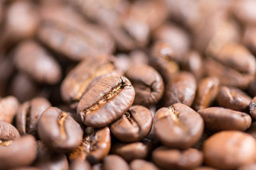 Coffee beans on a plate placed on a wooden table.