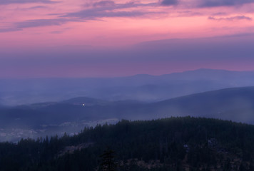 Sunset with distant hill and fog from Tristolicnik. Blue hour. Sumava National Park and Bavarian Forest, Czech republic and Germany
