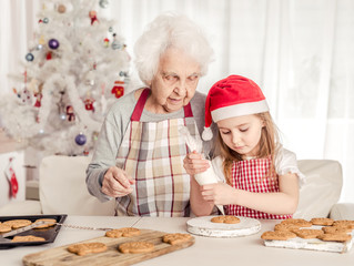 Grandmother teach granddaughter decorate cookies