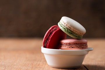 Pile of sweet and colourful french macaroons on wood background.