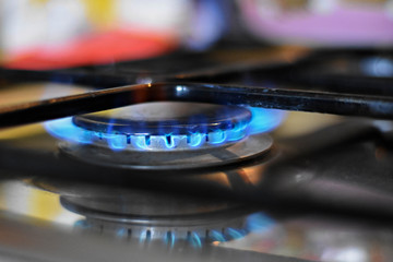 Natural gas burning on kitchen gas stove in the dark. Panel from steel with a gas ring burner on a...