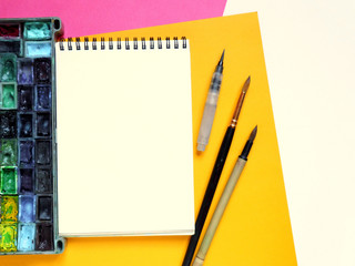 Template with blank notebook and drawing tools on white, yellow and pink paper background.