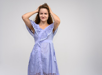 Studio portrait of a knee-length of a pretty girl student, brunette young woman with long beautiful hair in a dress on a white background. Smiling, talking, showing emotions